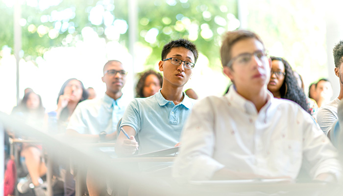 A group of students attend a lecture in a well-lit classroom.